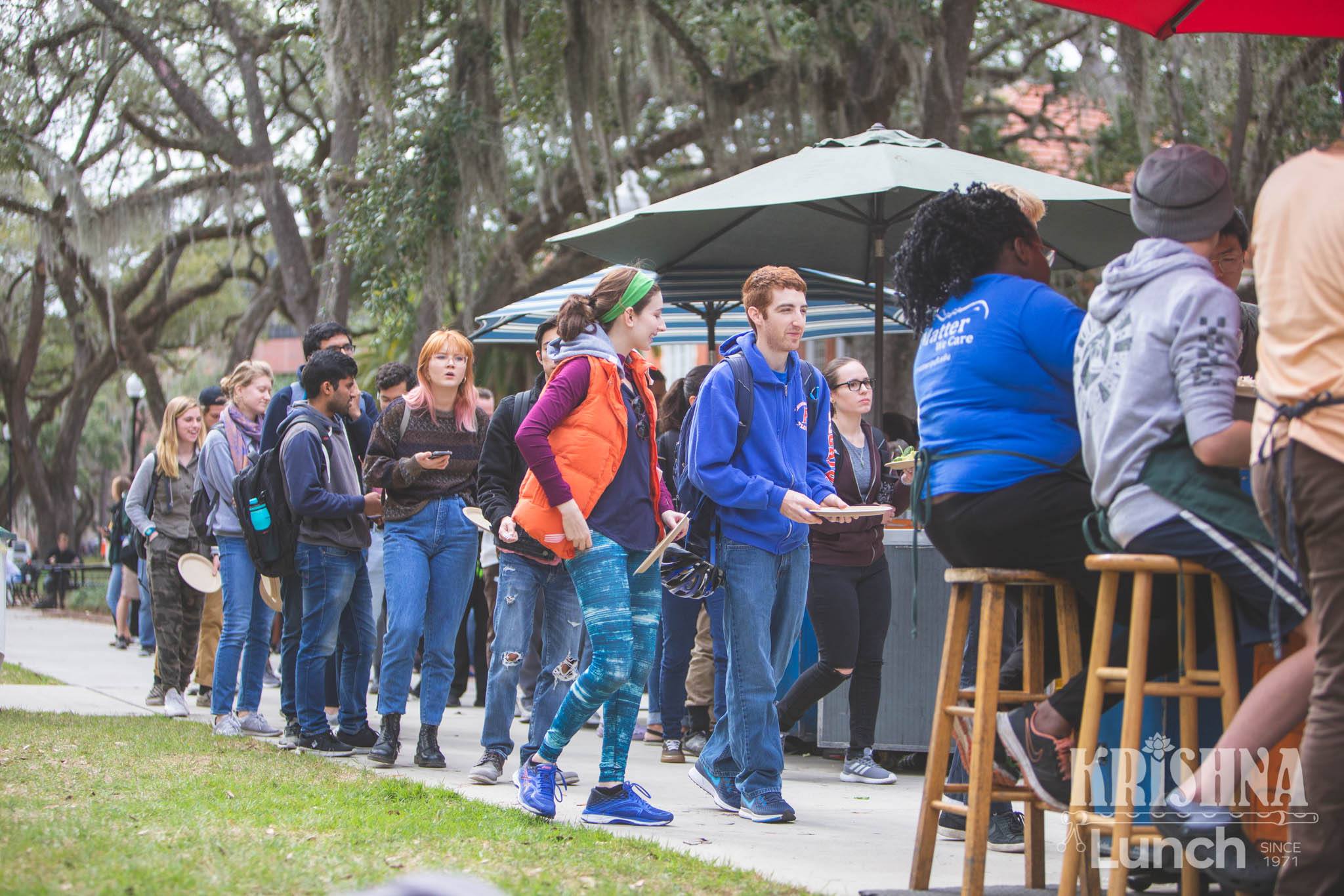 Students lining up for Krishna Lunch beneath the trees near the Plaza of the Americas